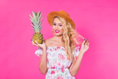 Bir ananas pembe bir arka plan üzerinde tutan mutlu genç kadın. Yaz, diyet ve tatil kavramı