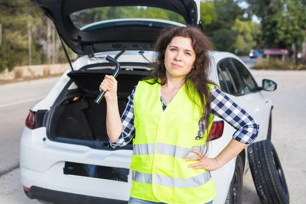 Joven mujer sostiene una llave en el fondo de un coche roto — Foto de Stock