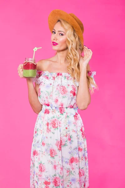 Jovem mulher bonita com smoothie verde no fundo rosa — Fotografia de Stock