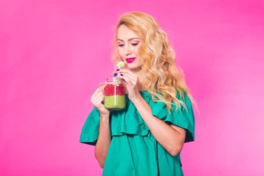 Pembe bir arka plan üzerinde yeşil güler yüzlü genç güzel kadın