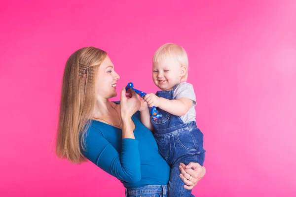 Jovem mãe e filha se divertindo juntos no fundo rosa — Fotografia de Stock