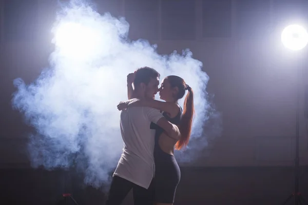 Young couple dancing social danse kizomba or bachata or semba or taraxia in dancing class background