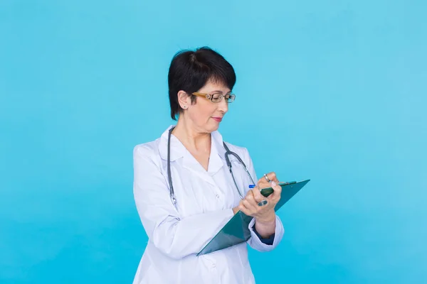Lekarz medycyny, pisanie receptę na niebieskim tle z miejsca kopii. — Zdjęcie stockowe