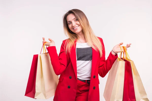 Porträt einer glücklichen, stylischen jungen Frau mit Einkaufstüten im roten Anzug — Stockfoto