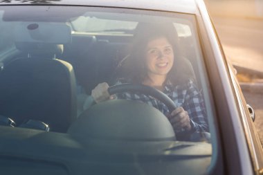 Kadın arabanın direksiyonuna parlak bir gülümseme ile