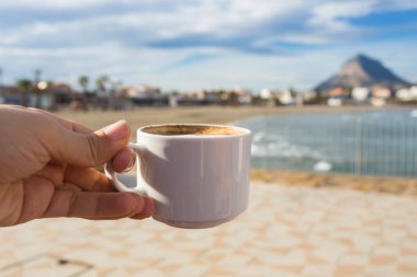 Güzel bir kumsal arka plan üzerinde elinde kahve.