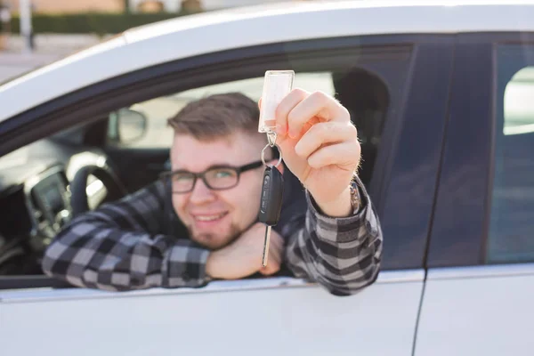 Щасливий молодий чоловік сидить в машині тримає ключі від машини — стокове фото