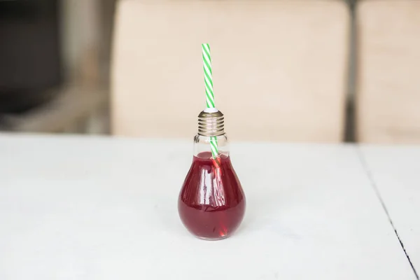 Sumo de laranja vermelho orgânico em um copo na forma de uma lâmpada — Fotografia de Stock