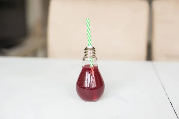 Zumo de naranja rojo orgánico en un vaso en forma de bombilla —  Fotos de Stock