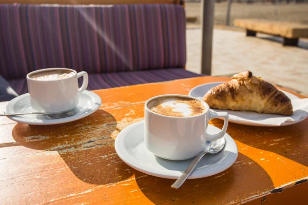 Duas xícaras de cappuccino revigorante e um croissant — Fotografia de Stock