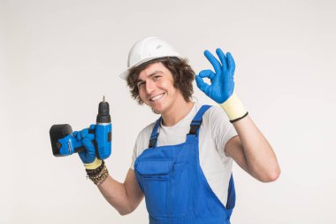 Stüdyo portre mutlu Builder kameraya eldiven ve beyaz kask giyiyor tornavida ile gülüyor.