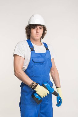 Eldiven ve mavi tulum giyen tornavida ile beyaz kask erkeklerde ciddi Oluşturucusu portresi.