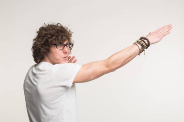 Komik beyaz t-shirt hareketle kıvırcık saçlı ayakta olan genç adam