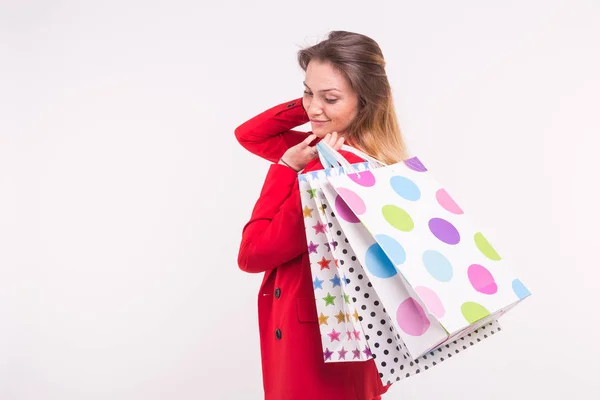 Retrato de mulher bonita em casaco vermelho com sacos de compras em suas costas com espaço de cópia . — Fotografia de Stock