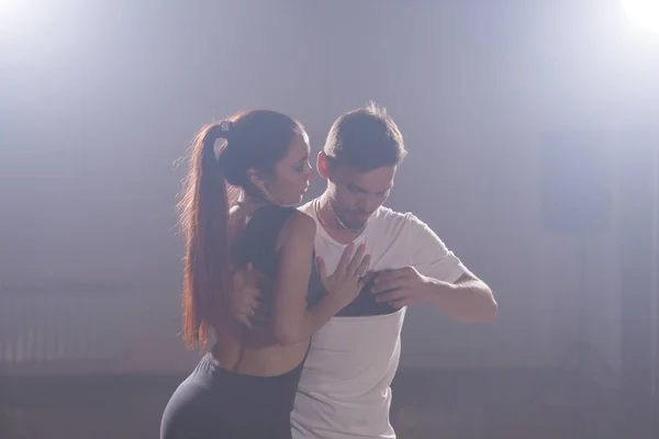 Bailarines hábiles actuando en la sala oscura bajo la luz del concierto y el humo. Pareja sensual realizando una danza contemporánea artística y emocional — Foto de Stock