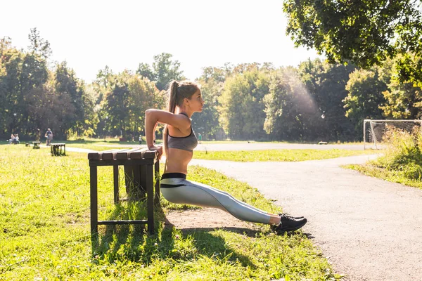 Jovem mulher apta a se exercitar, fazendo flexões ao ar livre — Fotografia de Stock