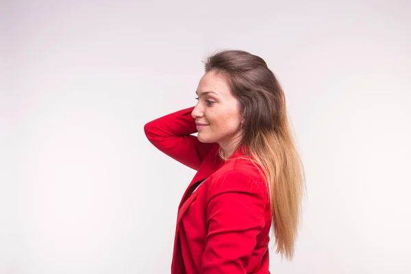 Jovem de jaqueta vermelha corrige o cabelo no fundo branco — Fotografia de Stock
