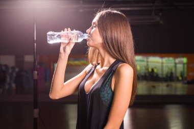 Genç kadın içme suyu spor salonunda uygun. Kaslı kadın egzersiz sonrası mola