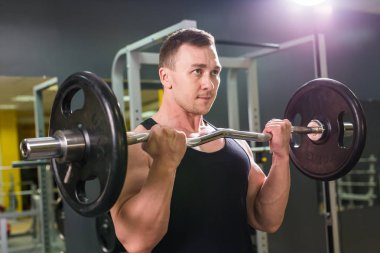 Güçlü vücut geliştirmeci barbell ile egzersizleri yapıyor. Güç ve motivasyon.