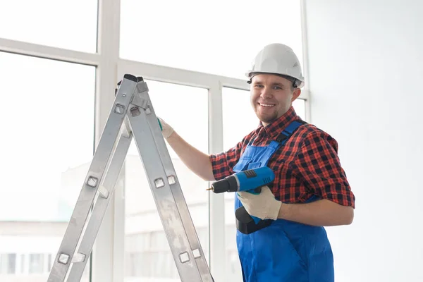 Happy male builder standing on ladder with drill infront of window. — Stock Photo, Image