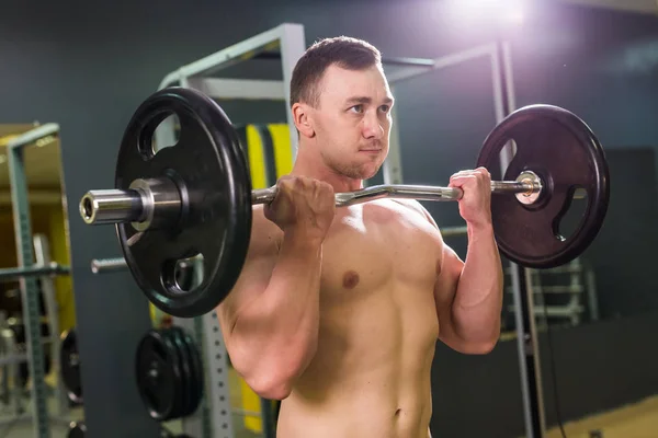 Muskulöser junger Mann stemmt Gewichte im Fitnessstudio — Stockfoto