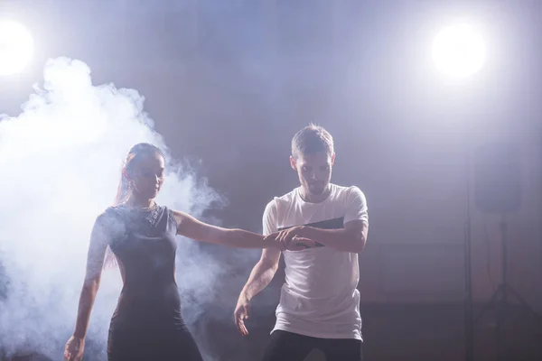 Bailarines hábiles actuando en la sala oscura bajo la luz del concierto y el humo. Pareja sensual realizando una danza contemporánea artística y emocional — Foto de Stock