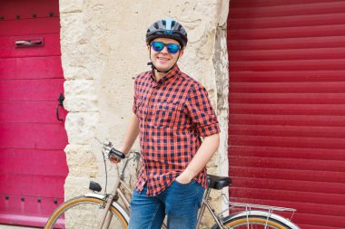 Adam kask, kırmızı gömlek ve güneş gözlüğü tutun bisiklet üzerinde açık