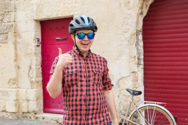 Komik adam kask ve kırmızı açık arka plan üzerinde bir yaşasın vererek güneş gözlüğü