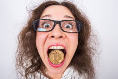 Altın bitcoin ağzına beyaz arka plan üzerinde tutarak komik bir kadının yakın çekim