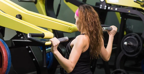 Fitness kvinna köra övningen med träningsmaskin i gymmet — Stockfoto