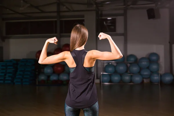 Mujer joven atlética mostrando músculos de la espalda y las manos en —  Fotos de Stock