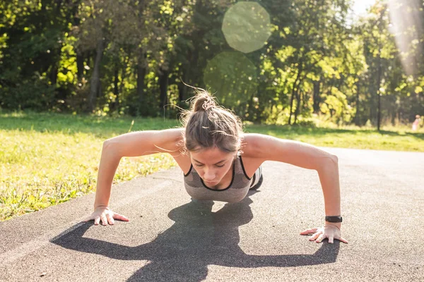 Mujer en forma joven haciendo ejercicio haciendo flexiones al aire libre —  Fotos de Stock