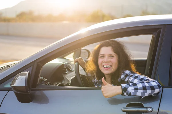 Glückliche Frau zeigt Daumen hoch und fährt ein neues Auto. positiver Gesichtsausdruck — Stockfoto