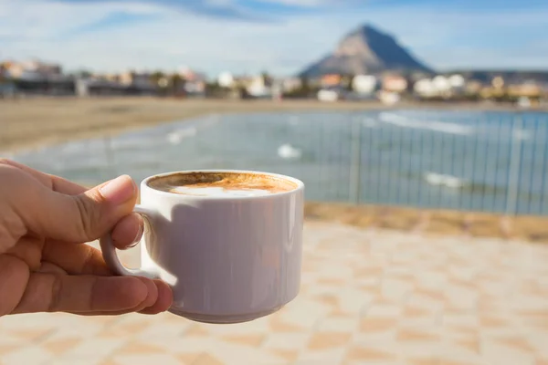 Xícara de café na mão no fundo de uma bela praia . — Fotografia de Stock