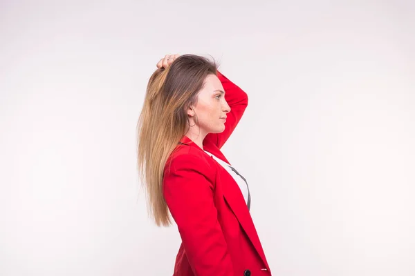 Saçları beyaz zemin üzerine kırmızı ceketli genç bayan düzeltir — Stok fotoğraf