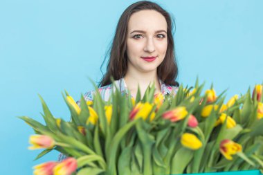 Büyük bir demet lale mavi zemin üzerine beyaz genç kadın.