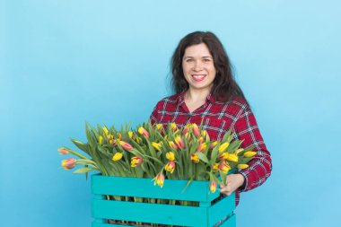 Lale mavi zemin üzerine kutusuyla tutan güzel kadın bahçıvan