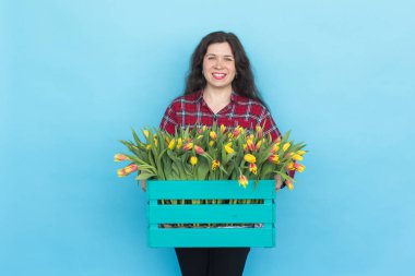Lale mavi zemin üzerine kutusuyla tutan güzel kadın bahçıvan