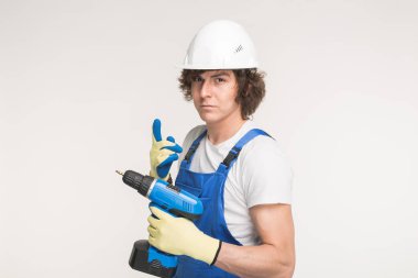 Eldiven ve mavi tulum giyen tornavida ile beyaz kask erkeklerde ciddi Oluşturucusu portresi.