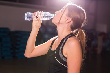 Fitness genç kadın içme suyu şişe. Kas genç erkek spor salonunda egzersiz bir mola.