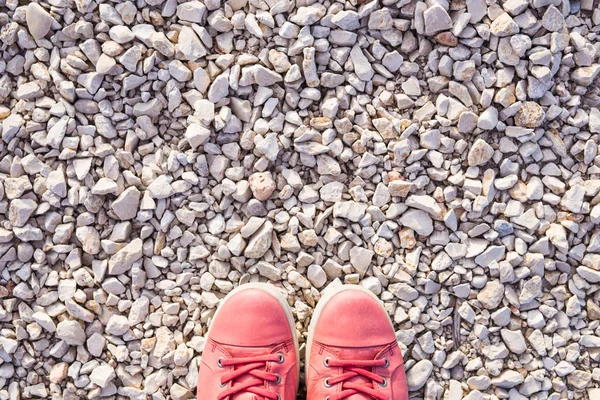 Röda sneakers på småsten, ovanifrån — Stockfoto