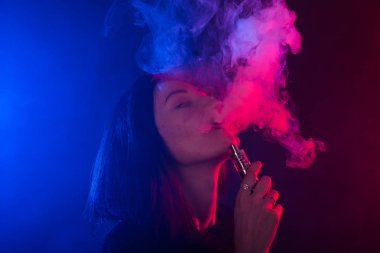 Asyalı kadın sigara vape veya e-sigara neon ışık siyah arka plan, portre