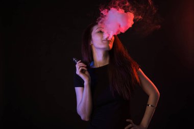 Neon ışık ve duman e-sigara veya vape siyah arka plan üzerine genç kadın