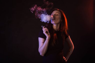 Asyalı kadın sigara vape veya e-sigara neon ışık siyah arka plan, portre.