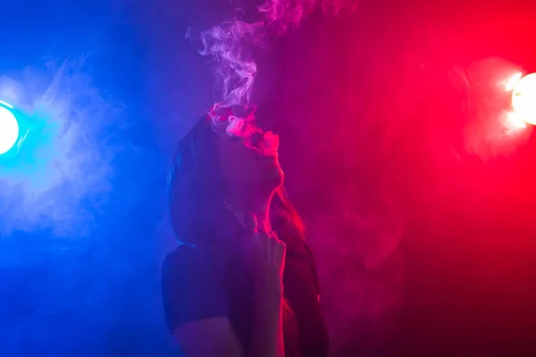 Young woman in black t-shirt vaping in red and blue neon light — Stock Photo, Image