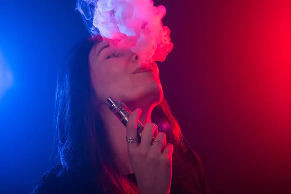 Portrait de jeune femme en néon rouge et bleu fumée avec vape ou e-cigarettes — Photo