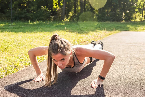 Giovane donna in forma esercizio facendo push-up all'aperto — Foto Stock