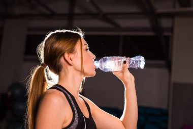 Fitness genç kadın içme suyu şişe. Kas genç erkek spor salonunda egzersiz bir mola.
