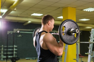 Güçlü vücut geliştirmeci barbell ile egzersizleri yapıyor. Güç ve motivasyon.