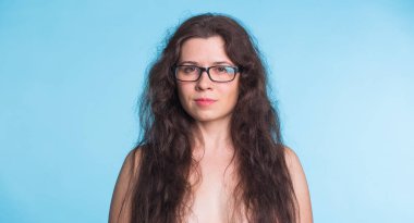 Vücut olumlu kavram-şehvetli üstsüz güzel kadın üzerinde mavi arka plan izole. Kameraya bakarak gözlük güzel kadın